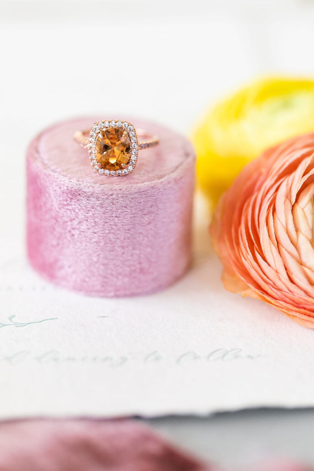 a peach wedding ring sits on top of a pink ring box